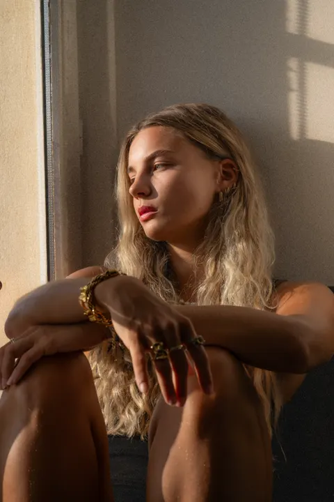 Portrait d'une jeune femme assise près d'une fenêtre, en lumière naturelle
