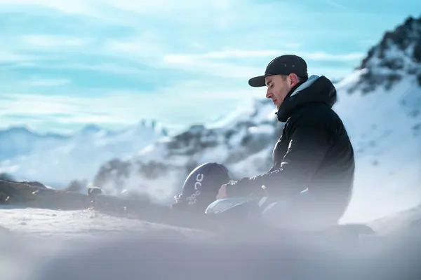 Skieur assis au sommet, dans la brume, au-dessus d'une mer de nuages