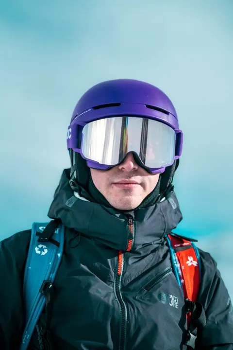 Portrait vertical d'une skieuse, masque violet, sur fond de glacier