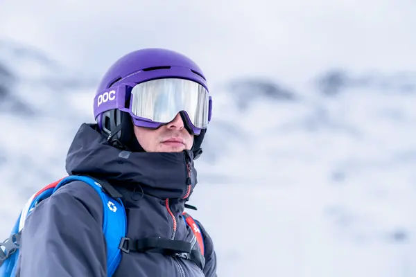 Portrait d'une skieuse casquée, masque violet, sous la neige